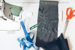 Jeans manufacturing. Flat lay of fabric pattern, scissors, tapeline on seamstress workplace.