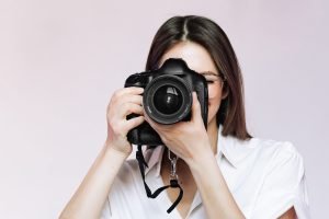 Female portrait of professional photographer with digital modern camera. Woman photo equipment for shooting indoors.